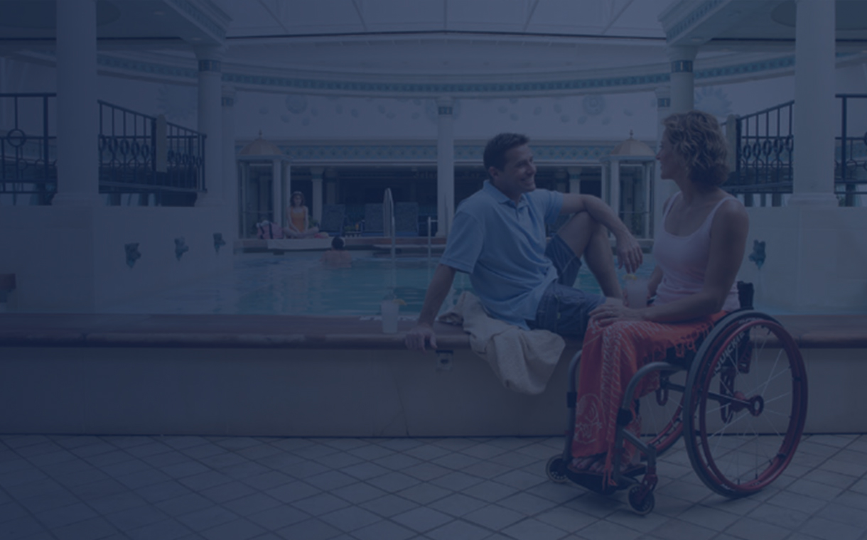 A couple in a wheelchair having a romantic moment by the indoor pool on our cruise ships