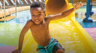 A male toddler smiling having fun in the water park onboard Royal Caribbean cruises