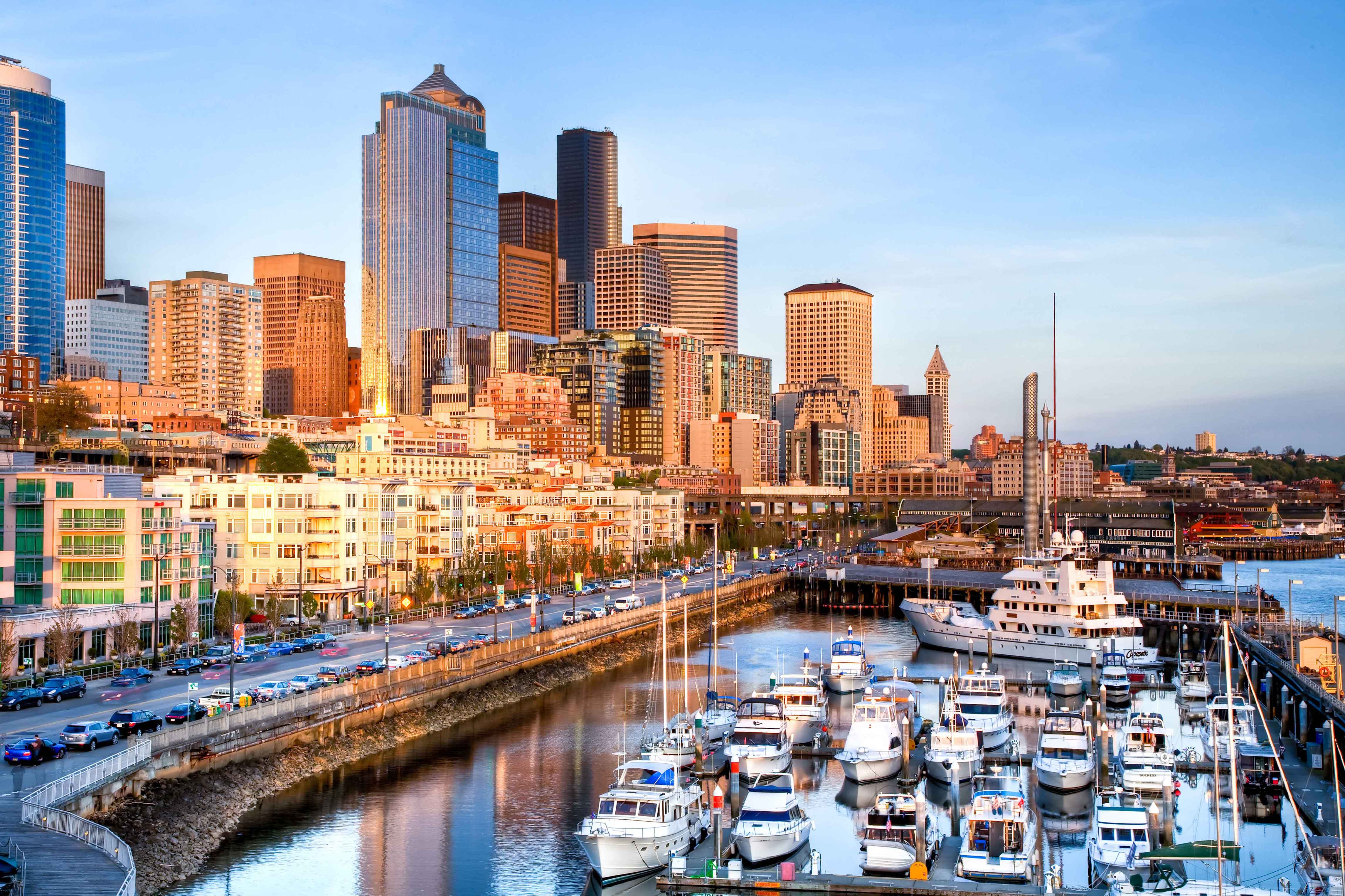 View of the waterfront with sail boats anchored along the dock and views of the city at a golden sunset hour in Seattle, Washington