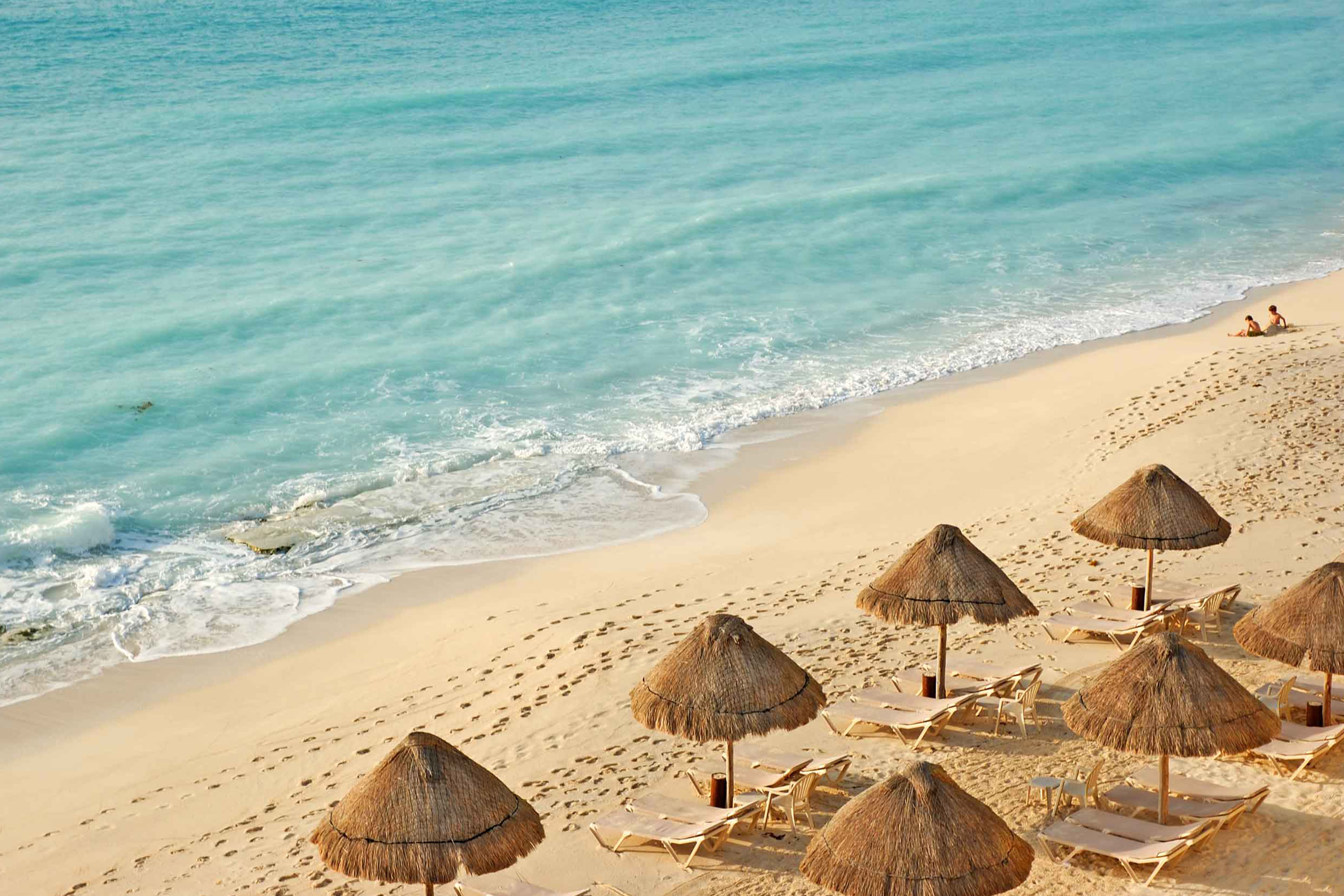 Malecon Beach with tanning chairs and tiki huts lined up along the shore in Yucatan, Mexico