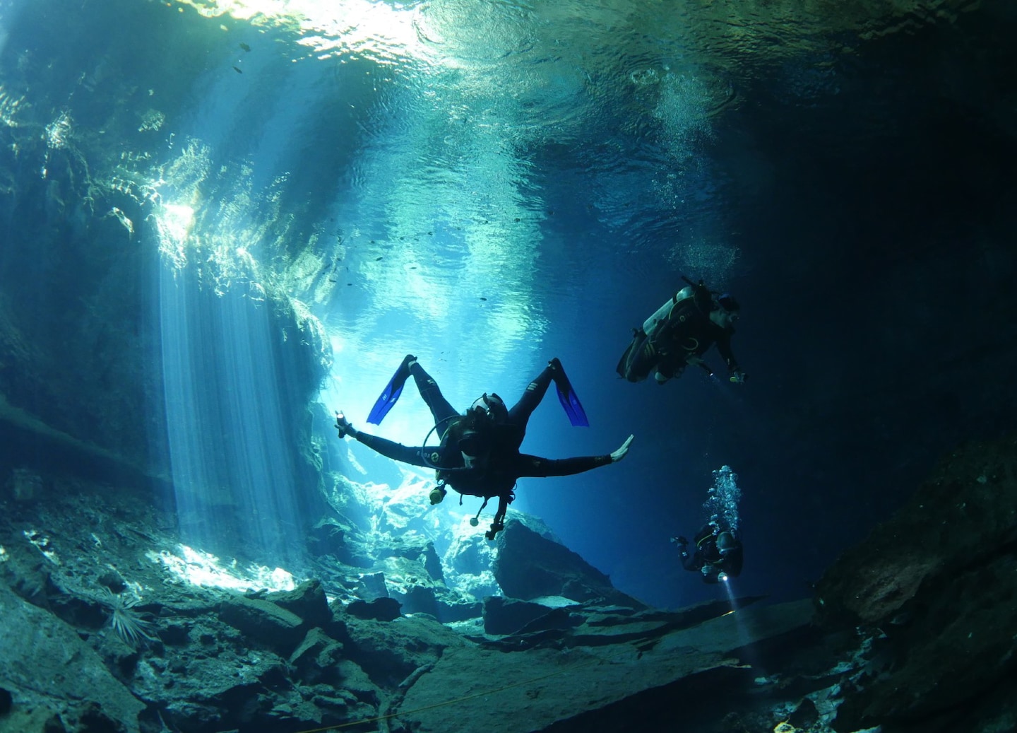 A scuba diver glides through a cenote, surrounded by clear water and dramatic cave formations. - Cozumel, Mexico 