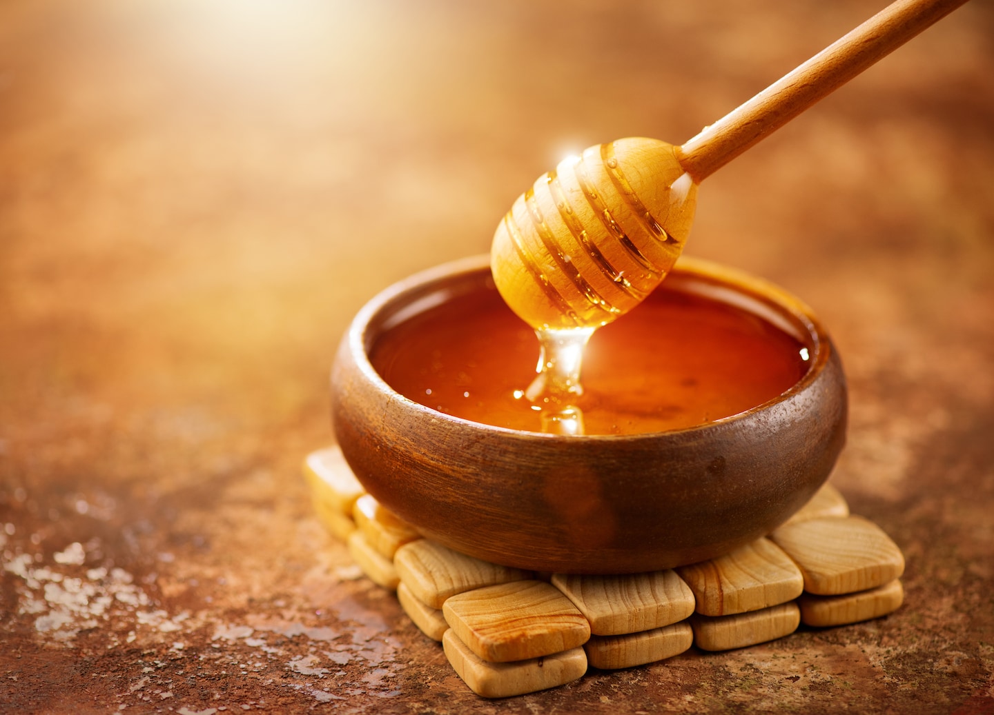 Honey bowl with wooden dipper on rustic wooden surface.
