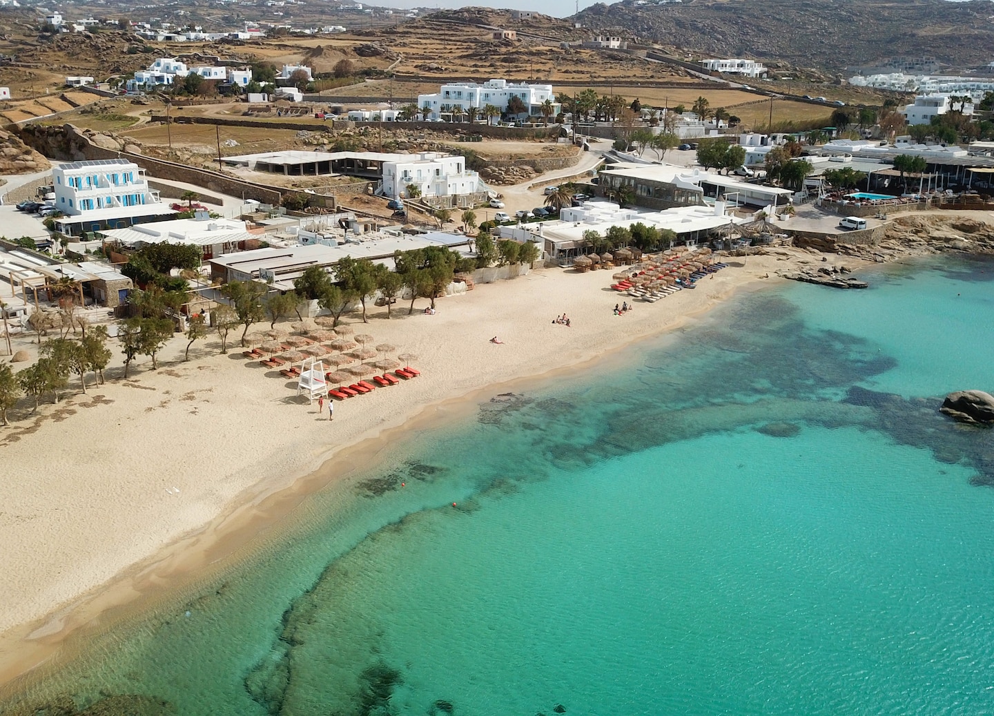 Paraga Beach’s turquoise water meets golden sand, with umbrellas and loungers lining the shore. - Mykonos, Greece
