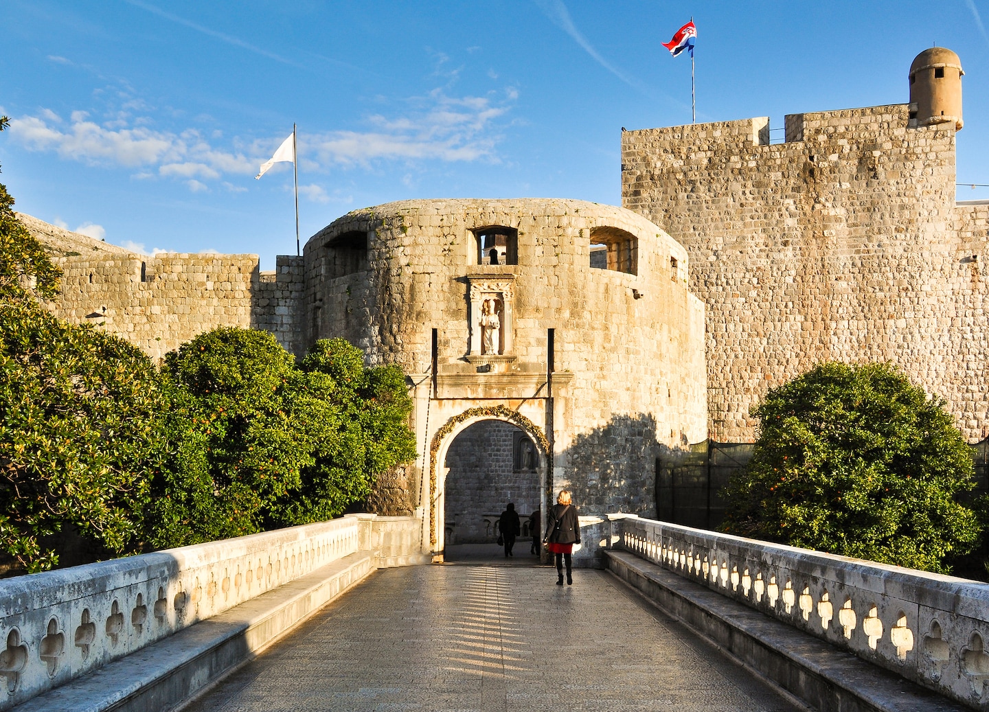 Pile Gate’s stone archway marks Dubrovnik’s historic entrance, surrounded by sturdy medieval walls. - Dubrovnik, Croatia