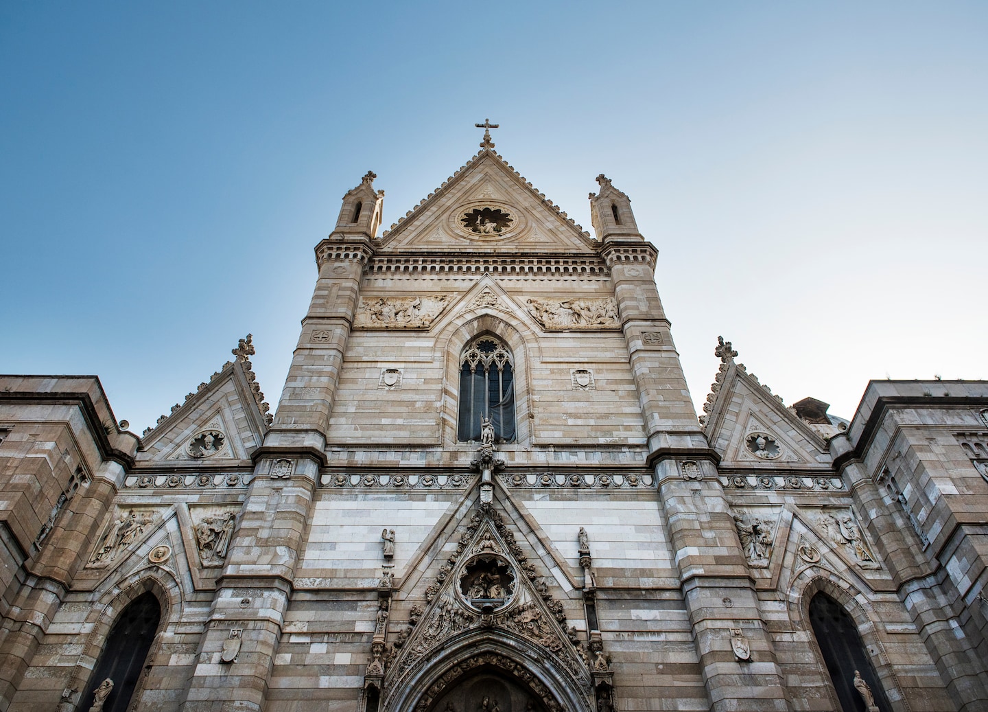 Naples Cathedral’s ornate façade features pointed arches, carved stone details, and a tall central tower. - Naples, Italy
