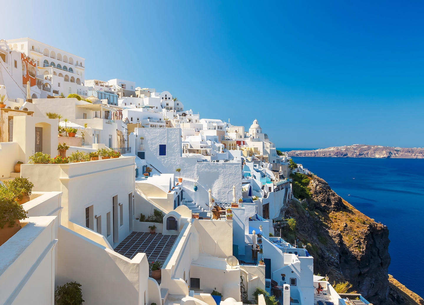 Fira’s white buildings overlook shimmering Aegean waters. - Santorini, Greece