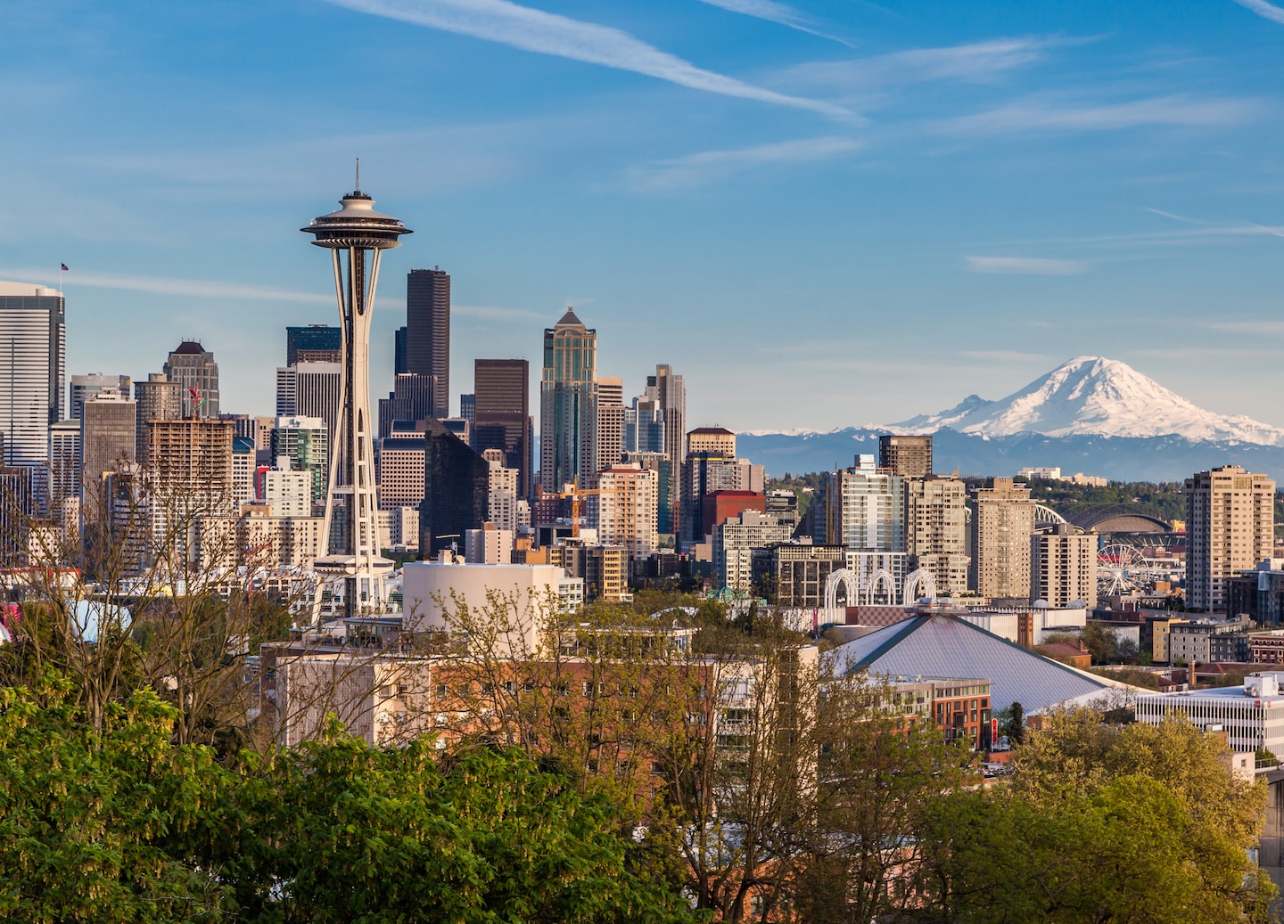 Seattle skyline rises before Mount Rainier under clear, blue sky. - Seattle, Washington