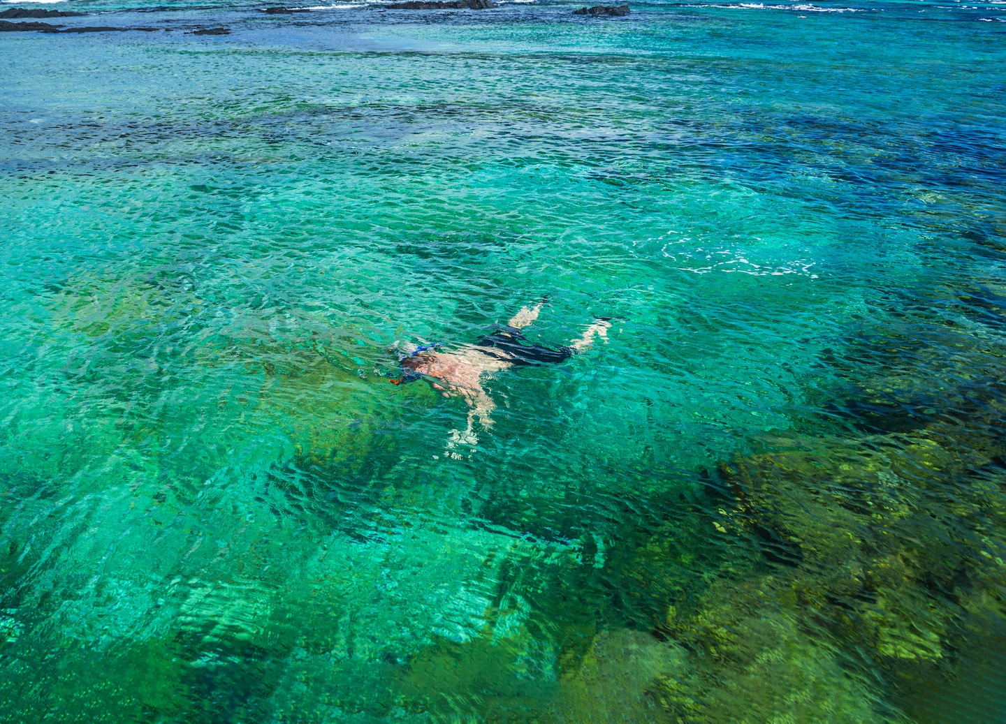 Kona’s curved bay meets deep blue water, backed by green hills and scattered oceanfront homes. - Kailua-Kona, Hawaii
