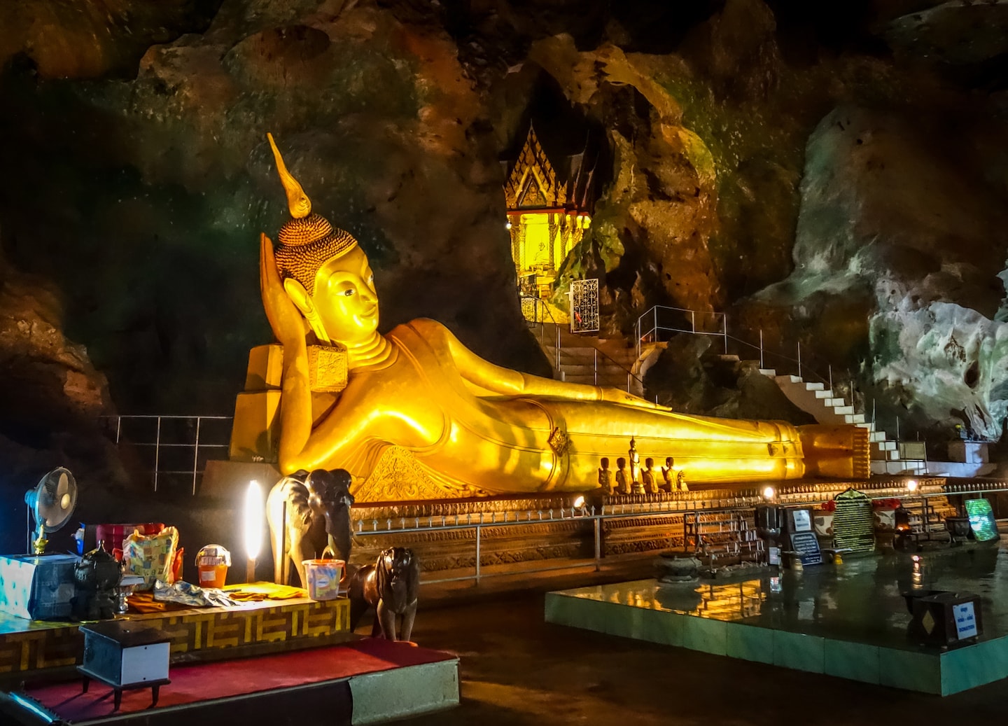 A golden Buddha statue sits peacefully inside Wat Suwan Kuha’s dim cave temple in Thailand. - Phuket, Thailand