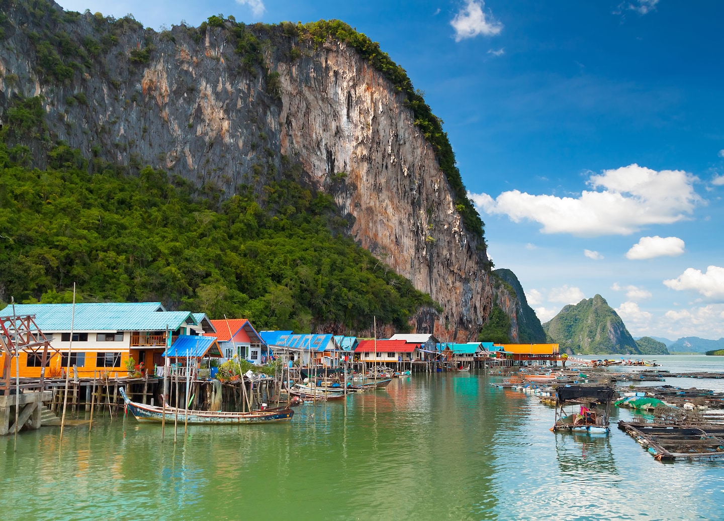 Ko Panyi’s stilted fishing village rises above calm water, backed by tall limestone cliffs. - Phuket, Thailand
