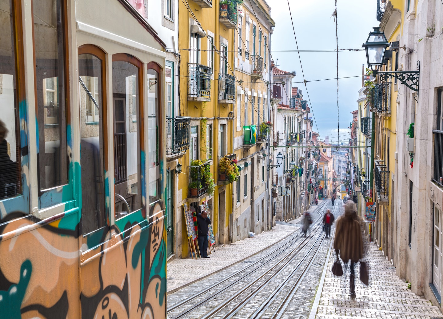 Lisbon’s tramway climbs Bairro Alto, passing colorful buildings under soft, cloud‑filtered daylight. - Lisbon, Portugal