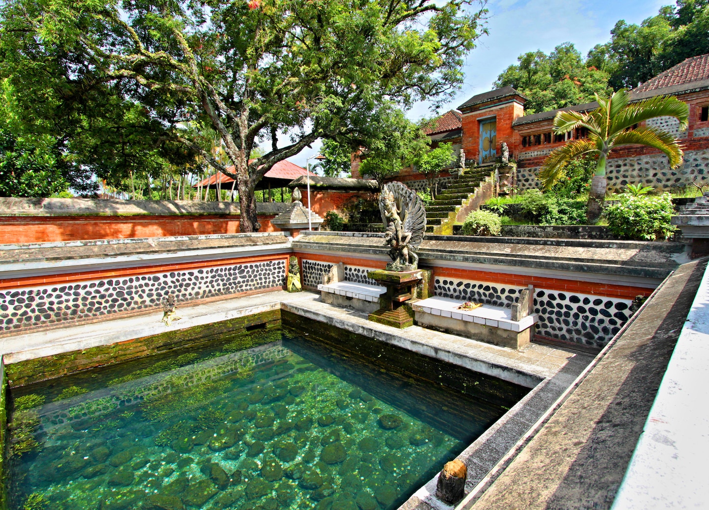 Historic Hindu temple with ornate stone gate and courtyard trees.