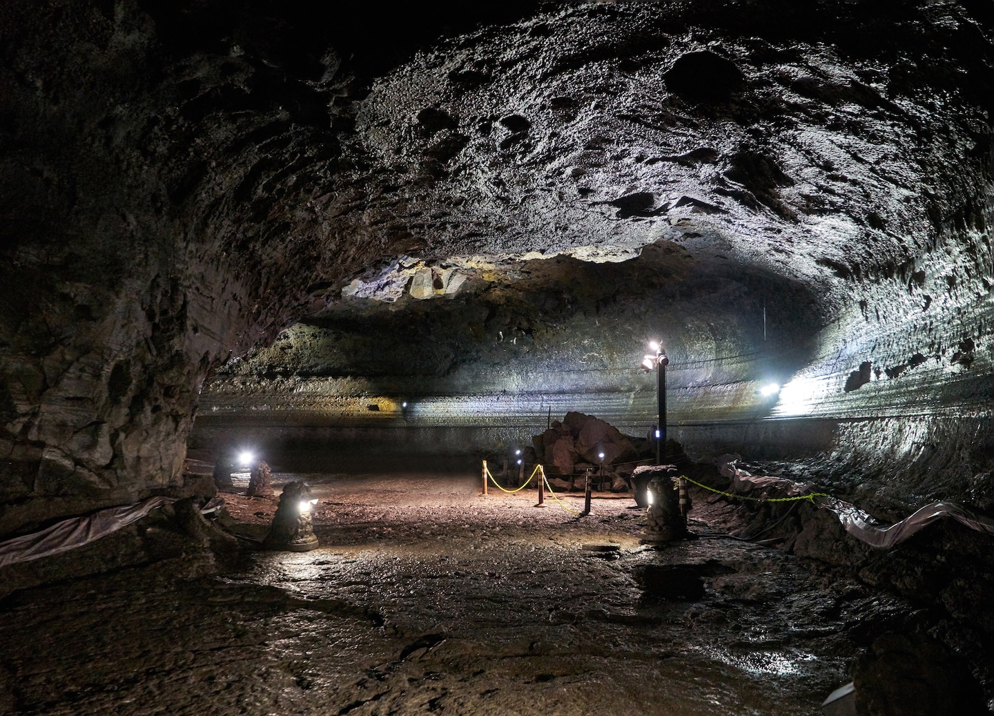 Manjanggul’s lava tunnel stretches through dark basalt walls, illuminated by soft lights along the walkway. - Jeju, South Korea