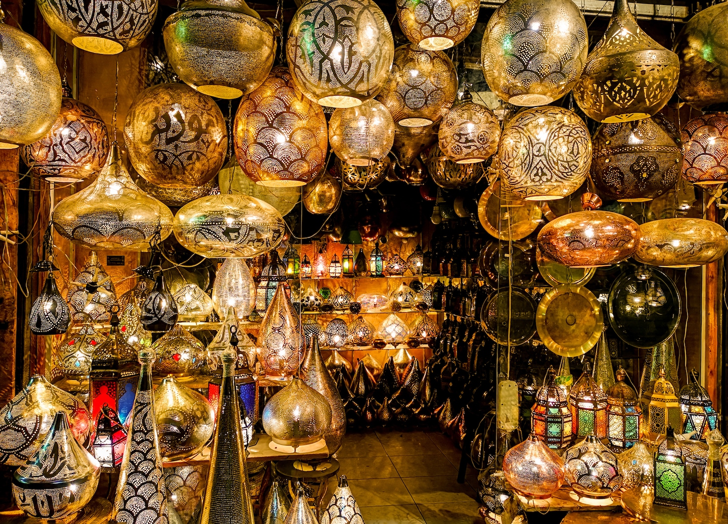 Handmade Egyptian metal lamps hang in rows, glowing with intricate cutout patterns. - Alexandria, Egypt