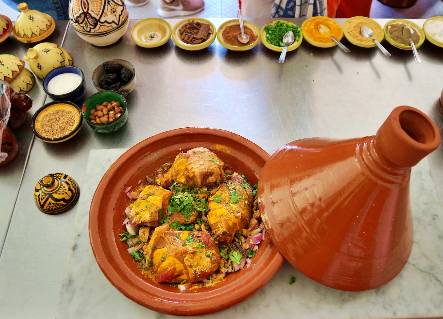 A Moroccan chicken tagine cooks with vegetables and spices inside a traditional clay pot. - Morocco