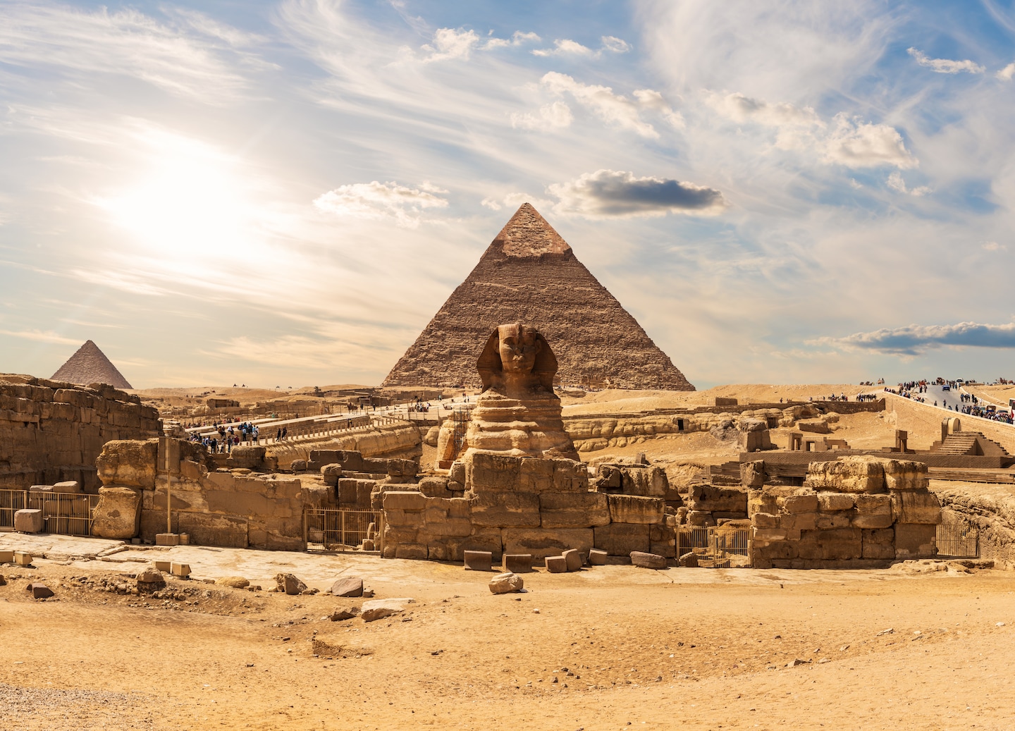 The Sphinx sits before the Great Pyramids, framed by warm desert light. - Giza, Egypt