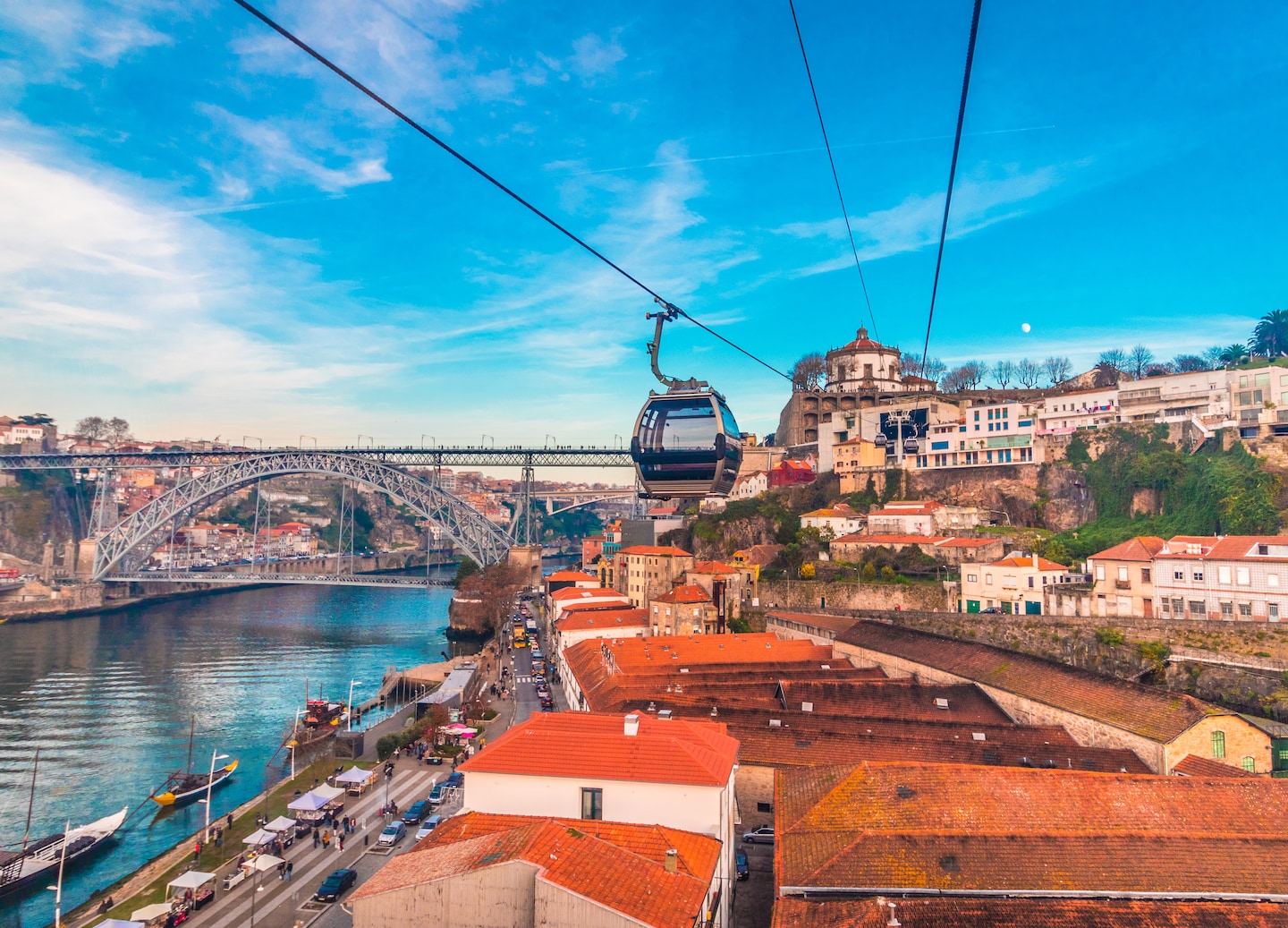 Cable car glides above Porto rooftops with Dom Luís I Bridge in the distance. - Porto, Portugal