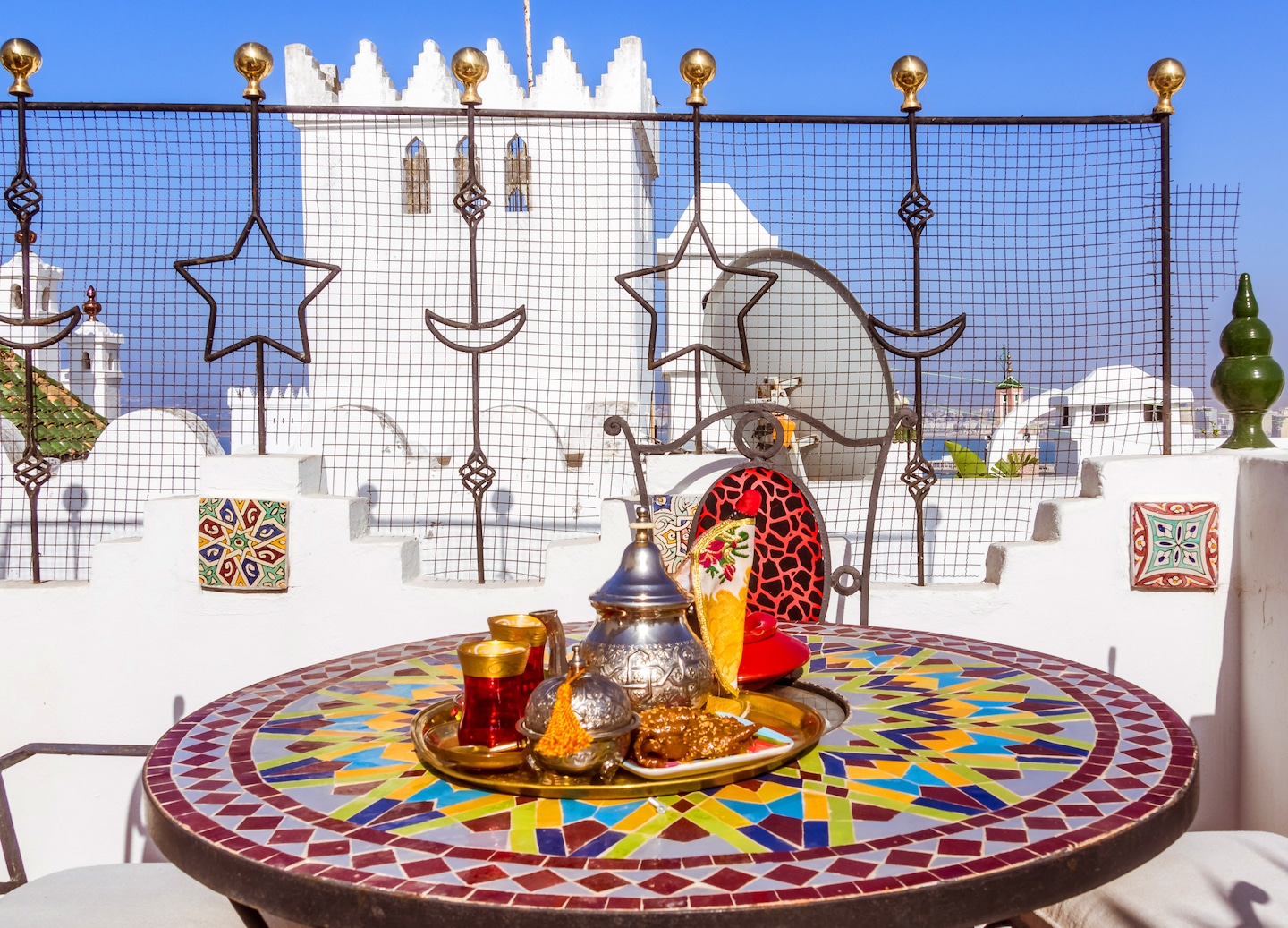 A rooftop terrace overlooks Tangier, with tea served beside warm sunlit views of the Kasbah. - Morocco