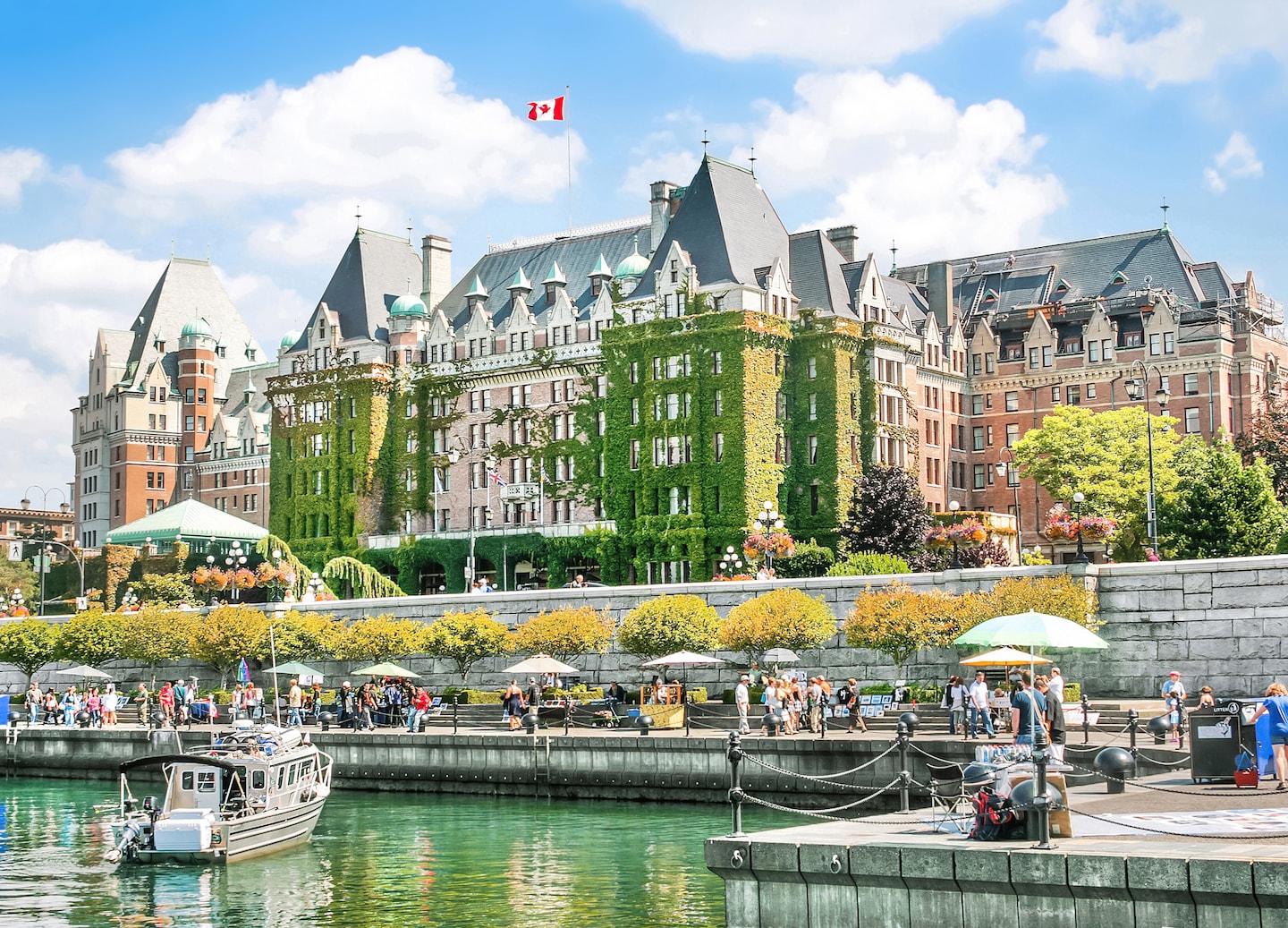 Victoria’s Inner Harbour shines with calm water, historic buildings, and moored boats under a bright sky. - Victoria, British Columbia