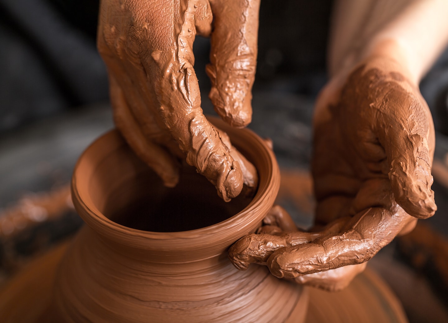Hands shape wet clay on a spinning wheel, forming a simple handcrafted pottery piece. - Cyprus