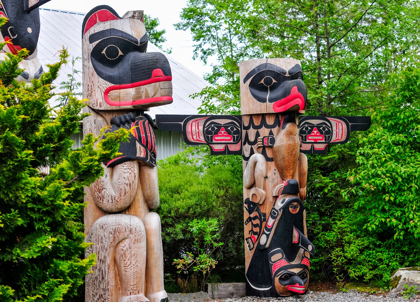 Beautiful animal totem poles rise among lush trees. - Ketchikan, Alaska