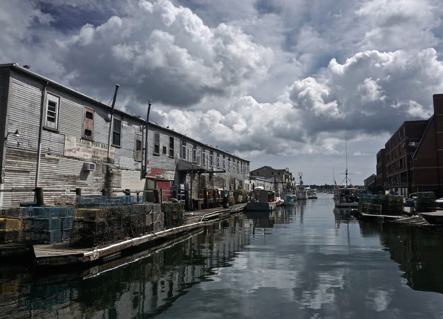 Portland’s waterfront features boats, piers, and colorful buildings reflecting along the calm harbor. - Portland, Maine