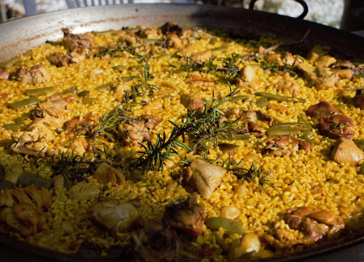 Traditional Valencian paella with chicken and rabbit cooks in a wide pan over saffron rice. - Valencia, Spain