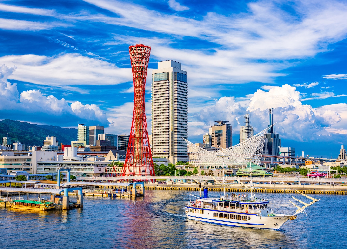 Kobe Port Tower rises beside the waterfront, with city buildings and a clear sky behind it. - Kobe, Japan
