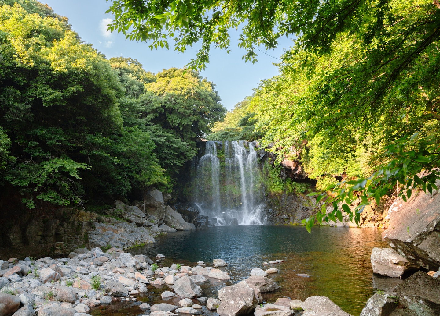 Cheonjeyeon Waterfall pours into a bright turquoise pool, surrounded by Jeju’s lush forest cliffs. - Jeju, South Korea