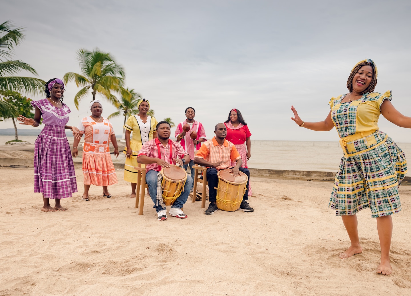Garifuna woman dances on a Belize beach, wearing traditional attire against bright Caribbean shoreline. - Belize City, Belize
