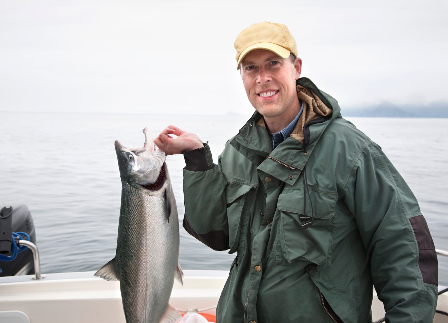 Smiling fisherman proudly holds fresh Alaskan salmon. - Sitka, Alaska
