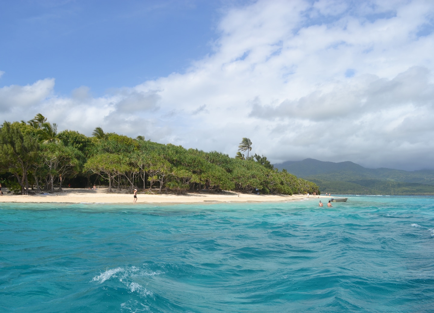 Mystery Island’s shoreline shows turquoise water, white sand, and lush green palms under bright sun. - Mystery Island, Vanuatu