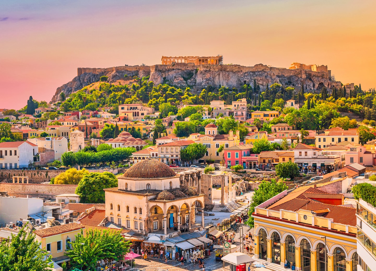 Monastiraki Square’s colorful rooftops sit below the Acropolis, glowing on the hill in Athens. - Athens, Greece