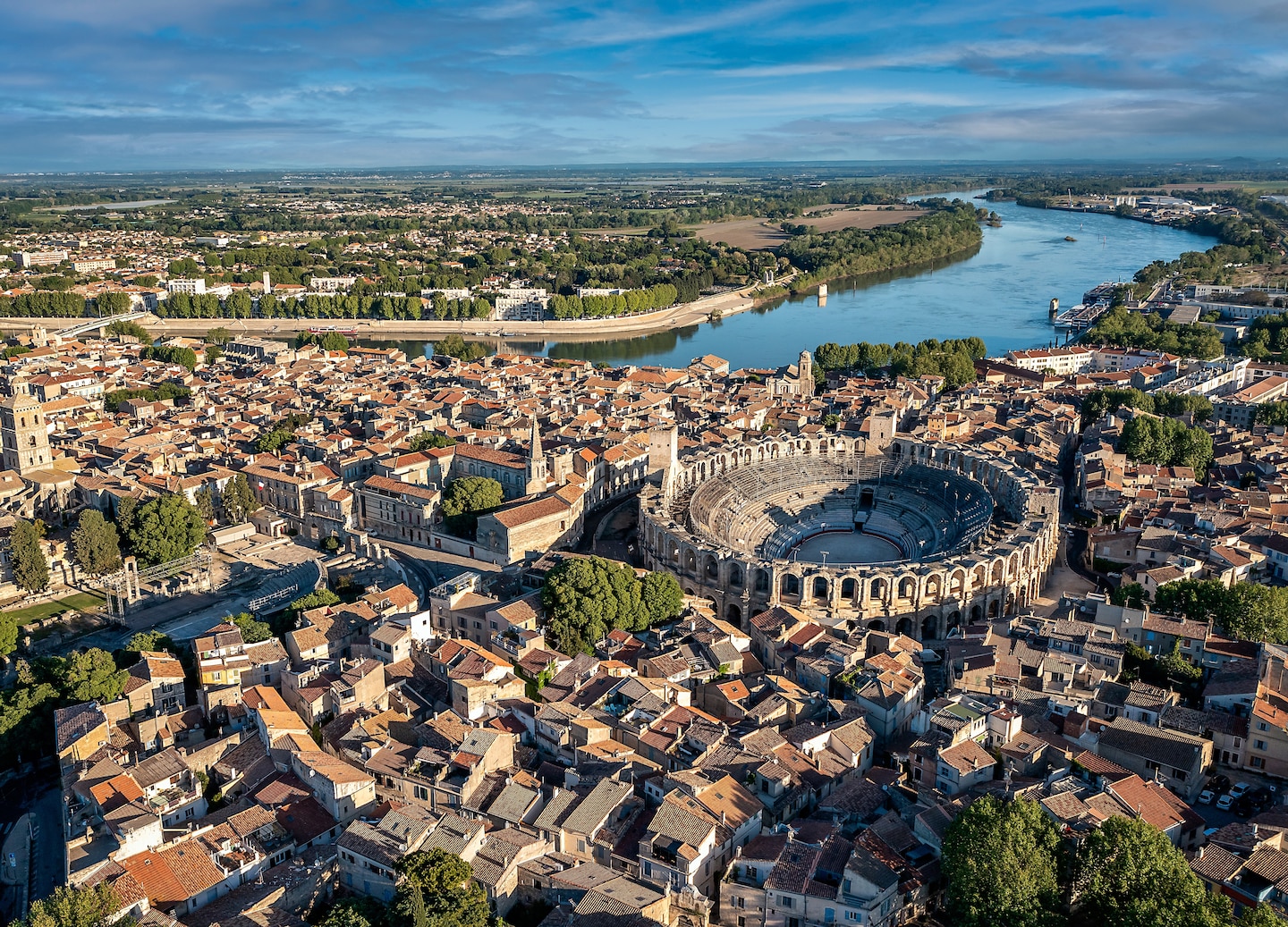 An aerial view of Arles reveals sunlit rooftops, Roman ruins, and surrounding Provençal countryside. - Provence (Marseille), France