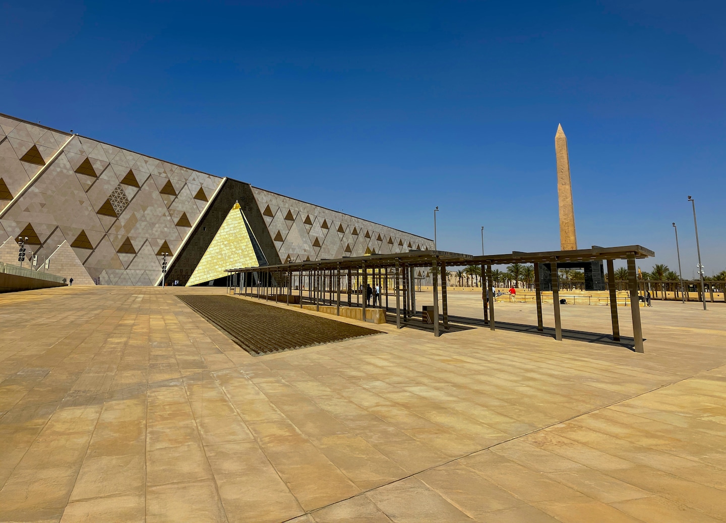 The Grand Egyptian Museum’s modern angular façade stands beside palm trees. - Cairo, Egypt
