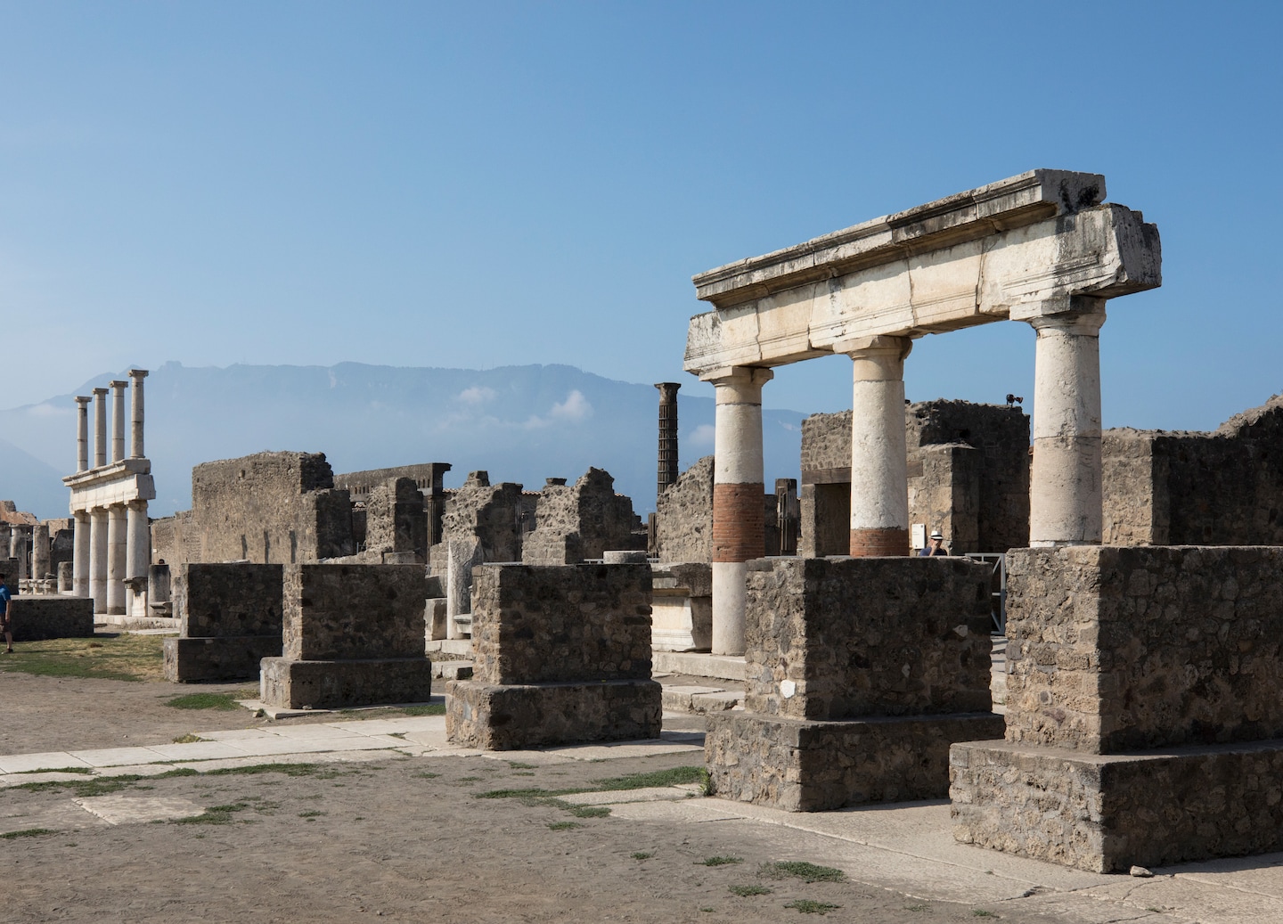 Ancient Pompeii columns stand amid stone ruins, with weathered walls showing the site’s volcanic past. - Pompeii, Italy 