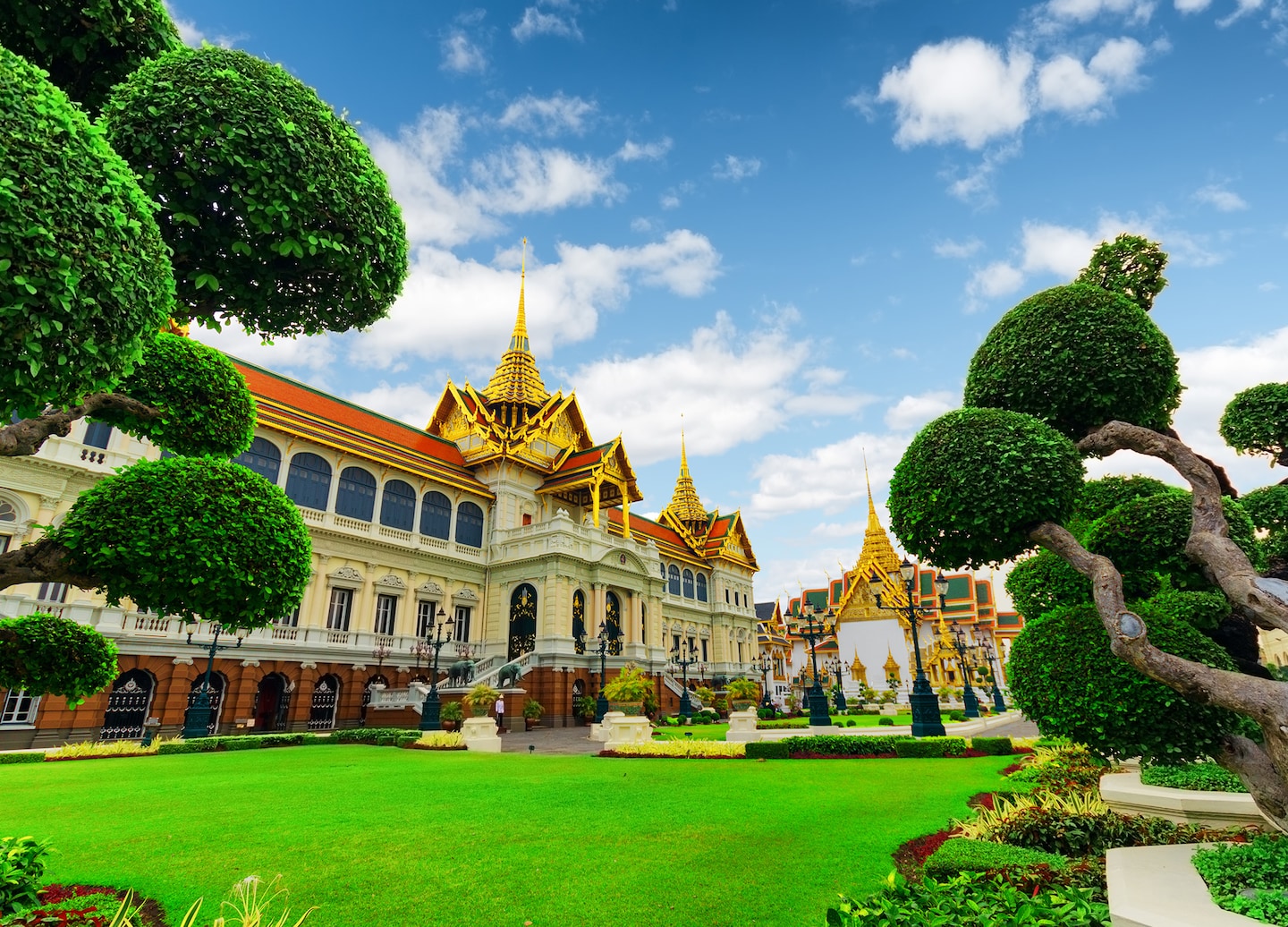 Bangkok’s Grand Palace features ornate golden roofs and white walls glowing under a bright blue sky. - Bangkok (Laemchabang), Thailand