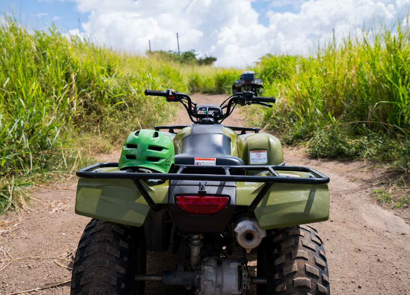 An ATV drives through tall green sugarcane fields, kicking up dust on a sunny St. Kitts trail. - Basseterre, St Kitts & Nevis