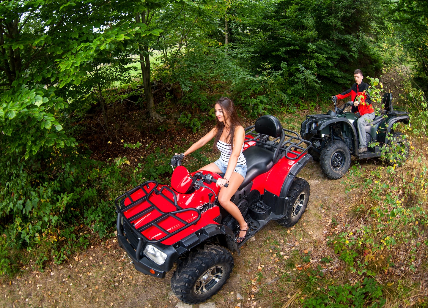 Couple rides ATVs on adventure trail.