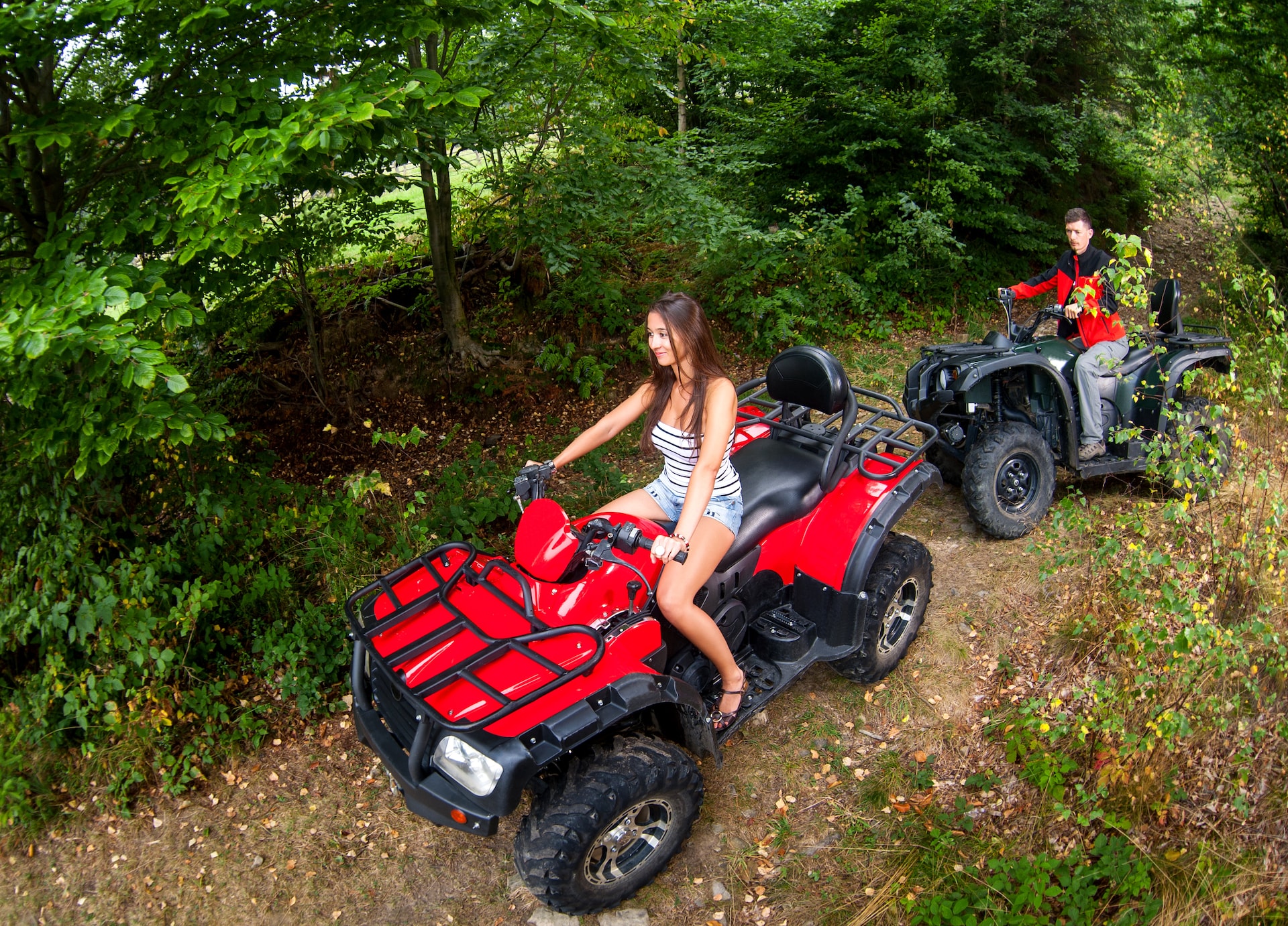 poeple man woman driving red atv in forest