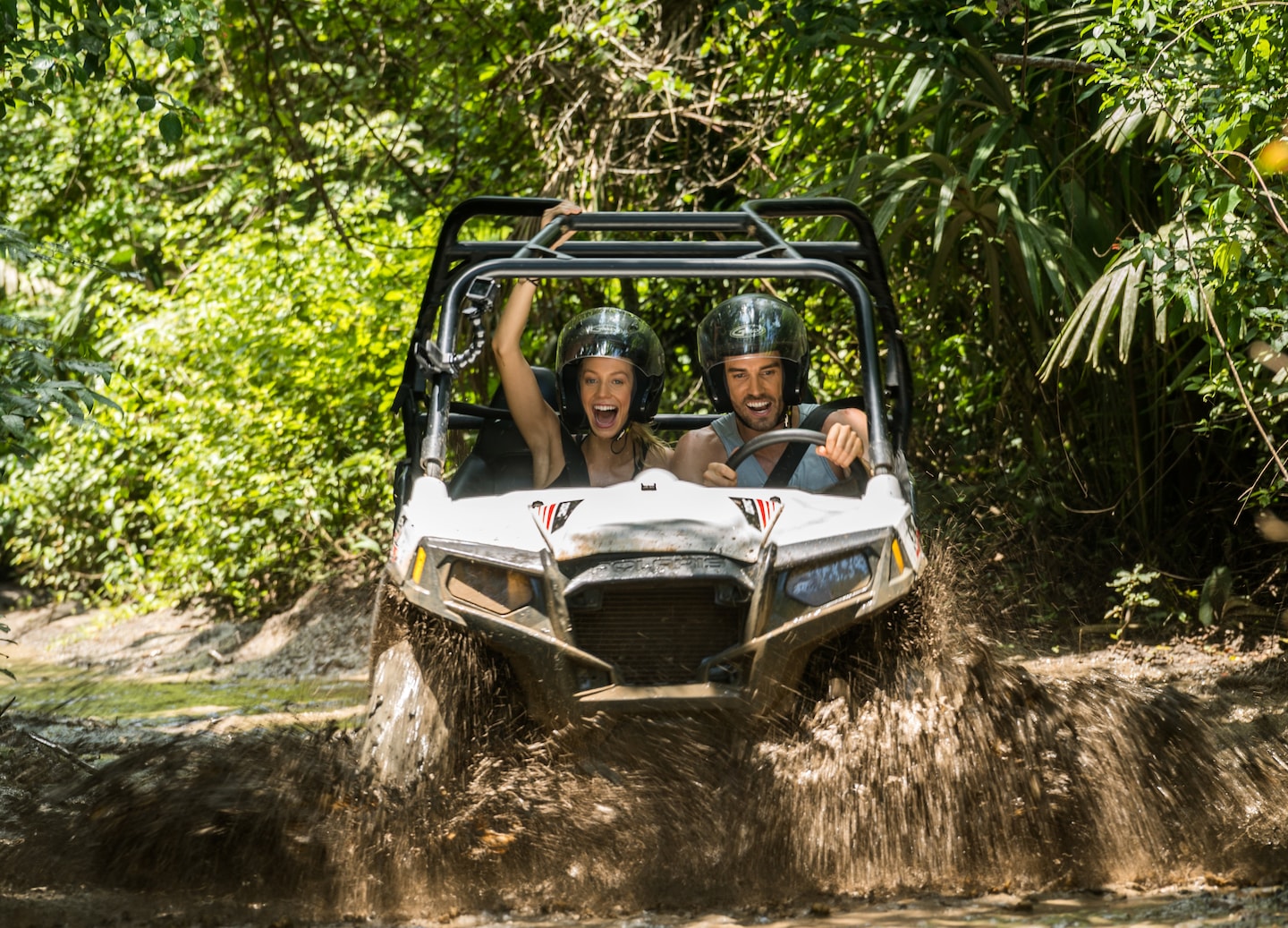 A caged 4x4 jungle buggy splashes through thick mud. - Belize City, Belize