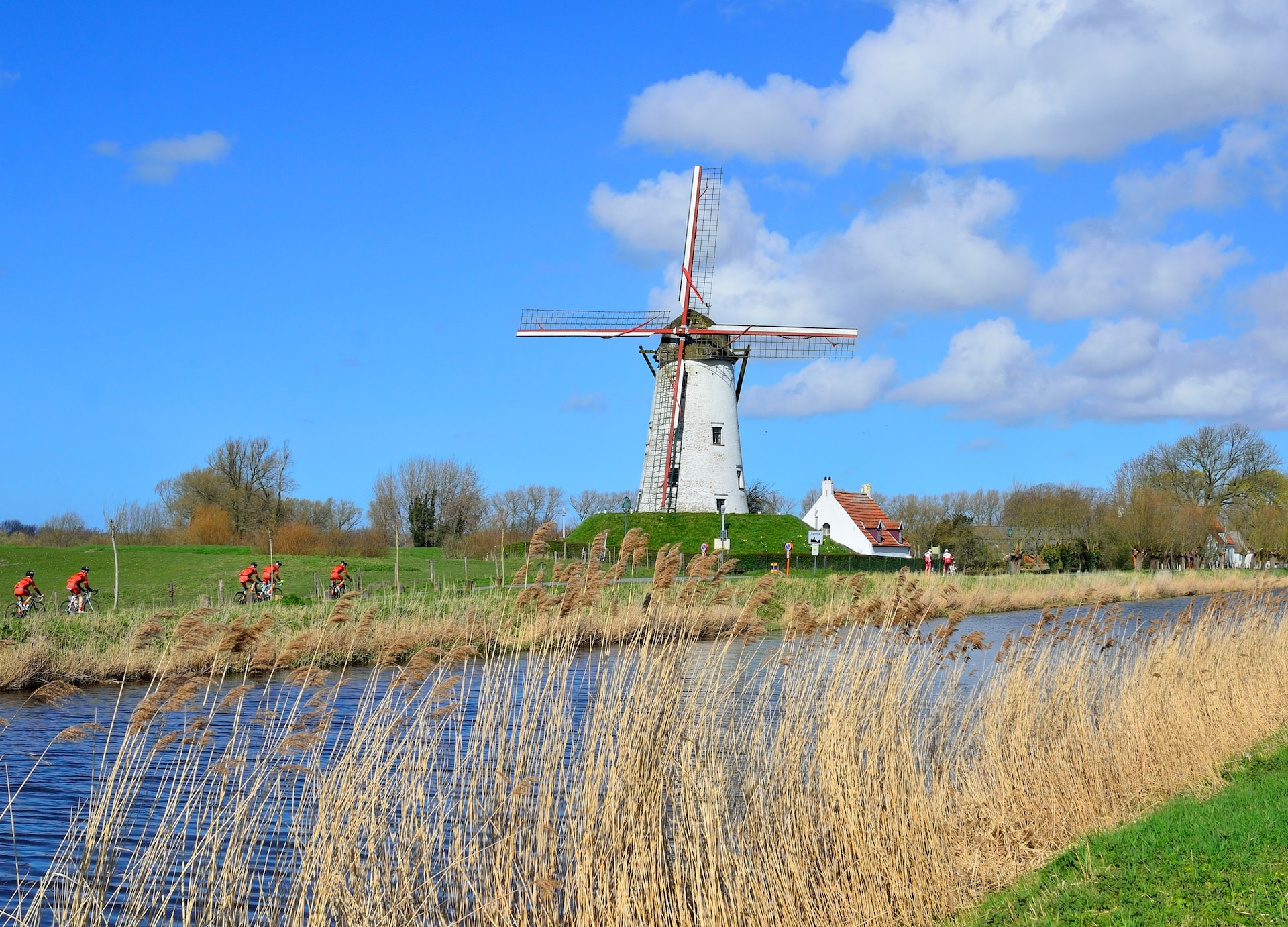 bikers passing by an old windmill in damme near bruges flanders belgium