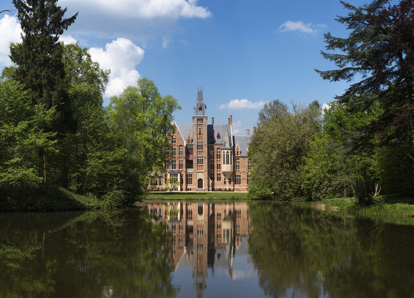 A quiet canal reflects the stone walls of a historic Flanders castle. - Belgium