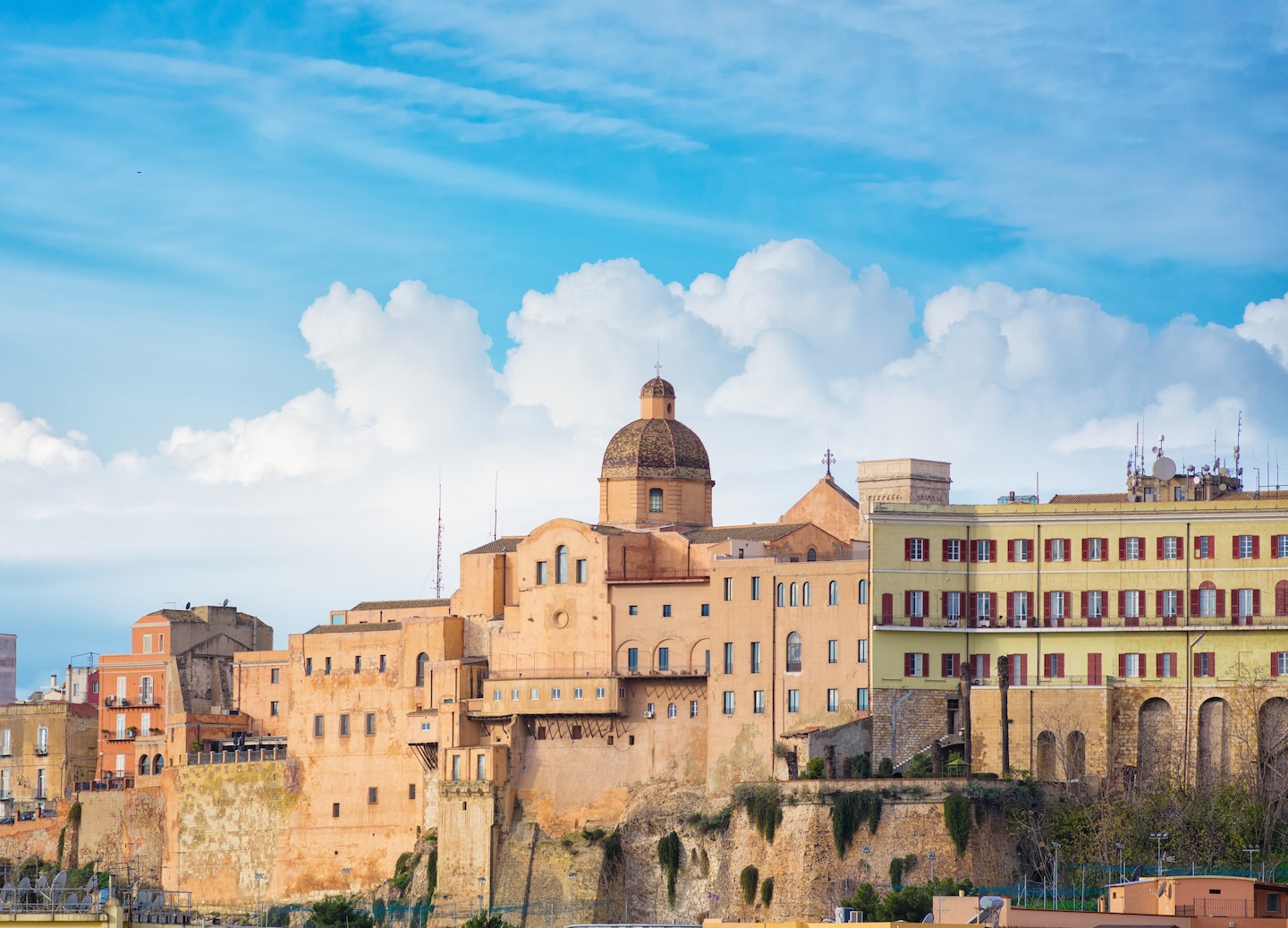 Cagliari’s hillside buildings overlook the harbor and coastline under bright Sardinian sunlight. - Sardinia, Italy