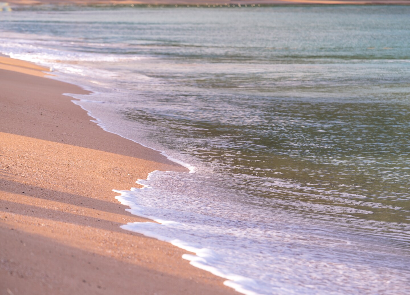 Ocean waves crashing onto sandy beach under bright coastal sky. - Castries, St. Lucia