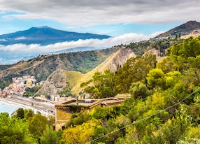 the smoking etna under the fall clouds behind the cost of the ionian see taormina giardini naxos