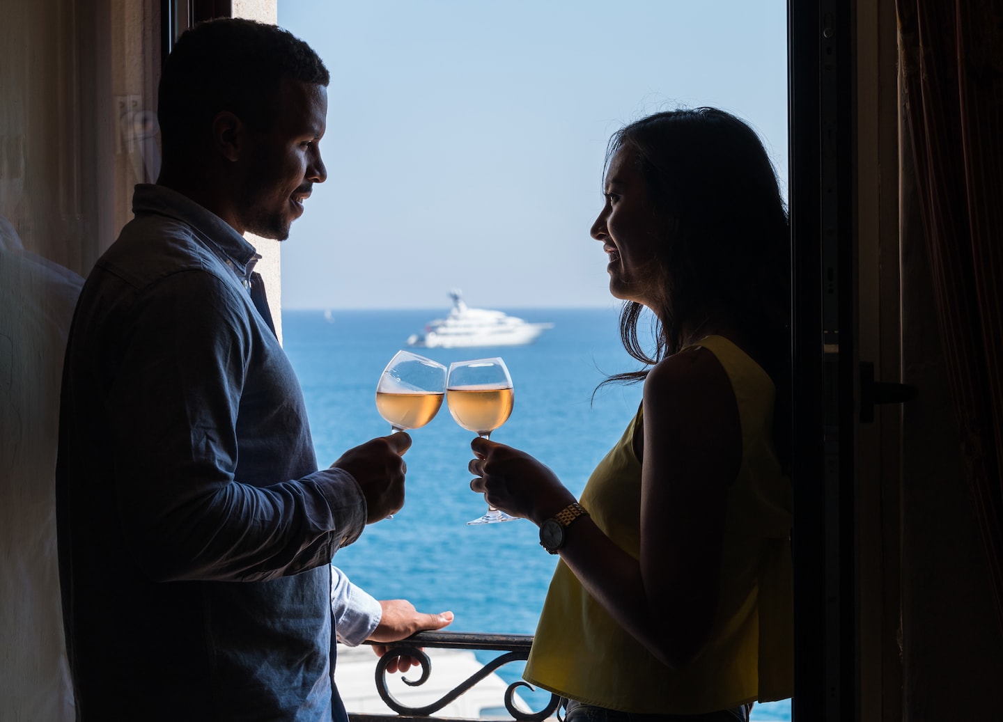 A couple clinks wine glasses aboard a boat, with calm blue water stretching behind them. - Chania, Crete, Greece
