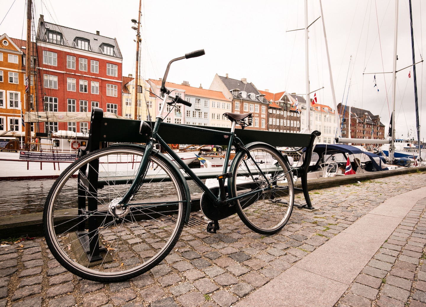A bicycle rests beside Copenhagen’s river on a calm, overcast day. - Copenhagen, Denmark
