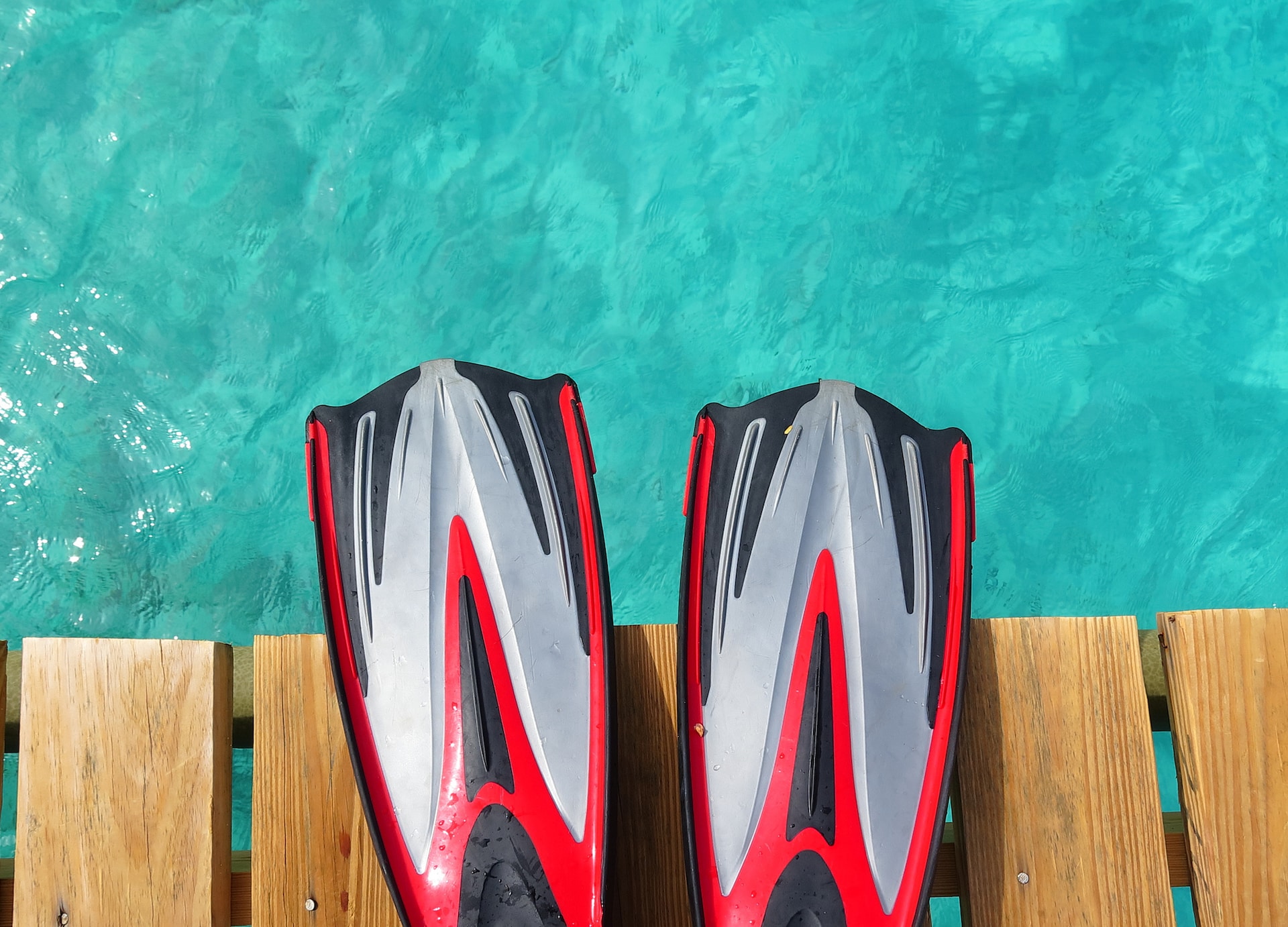 pair of scuba fins on the pier above the tropical sea red fins over the blue water tropical