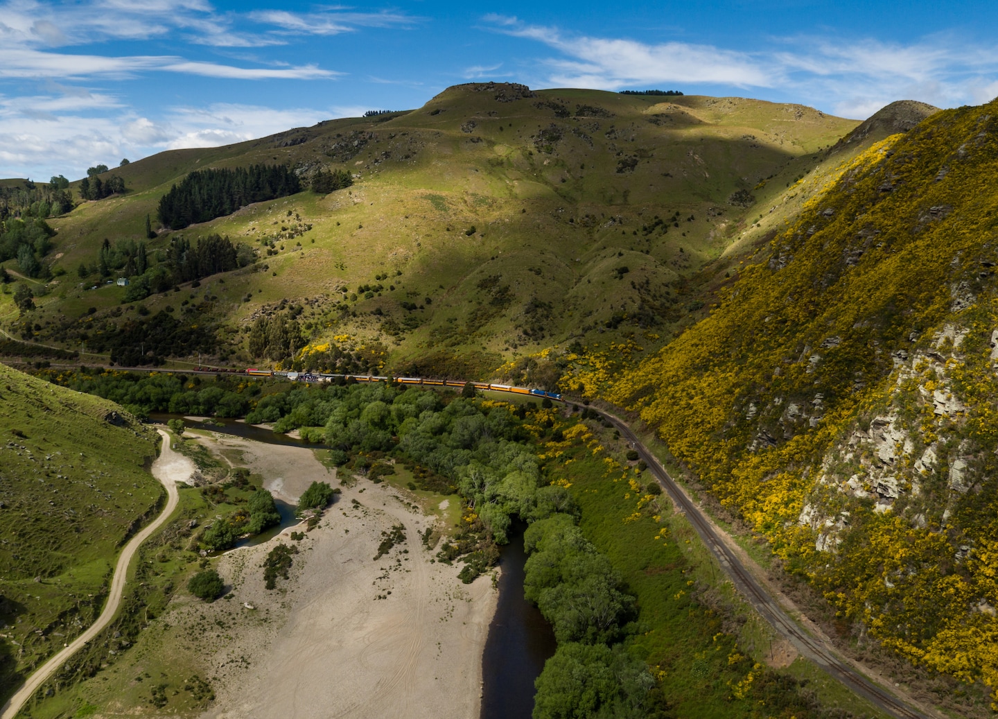 Vintage Taieri Gorge train crossing bridge through steep green mountains in Dunedin.
